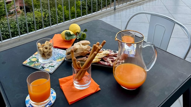 A table with food and drinks on a balcony overlooking a mountainous landscape. - Scario Club (San Giovanni a Piro)