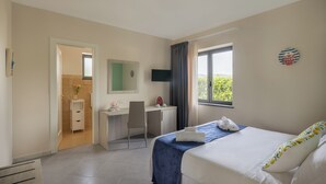 A hotel room with a bed, a desk, a chair, a TV, and a window with a view. - Scario Club (San Giovanni a Piro)
