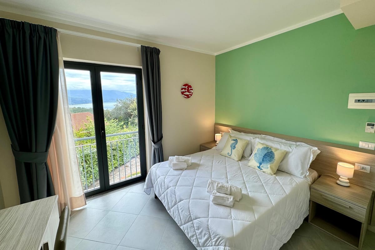 Une chambre d’hôtel avec un lit, une table de chevet, une table et une vue sur l’extérieur.