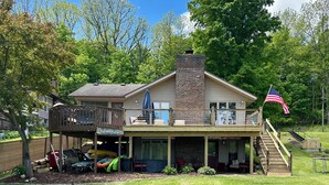 Une maison à deux étages avec une terrasse, un porche couvert et un drapeau américain.