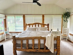 Une chambre à coucher avec un lit en bois, une literie blanche et un ventilateur de plafond.