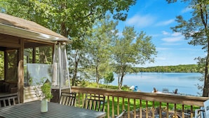 A wooden deck with a table and chairs overlooking a lake.