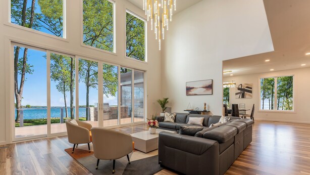 Un salon spacieux avec un grand canapé, une table basse et une vue sur le lac grâce à de grandes fenêtres.