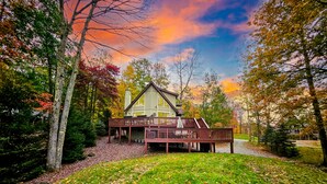 Une cabane dotée d’une terrasse, entourée d’arbres et bordée d’une pelouse.