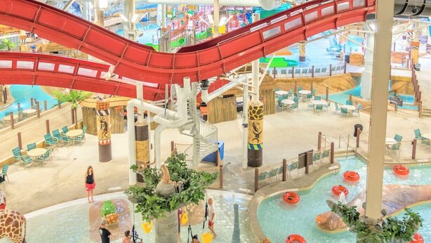 An indoor water park with a red water slide, multiple pools, and various water play areas. - Arrowhead Lake Retreat by AvantStay | Shared Pool, Game Room, Firepit (Pocono Lake)