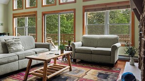 A spacious living room with a large window, a sofa, a coffee table, and a rug.