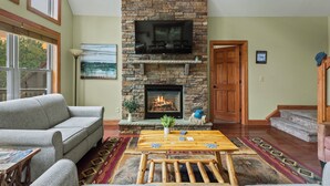 A living room with a stone fireplace, a flat-screen TV, and a sofa.