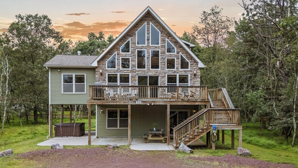 A two-story cabin with a stone facade, a balcony, and a covered porch.