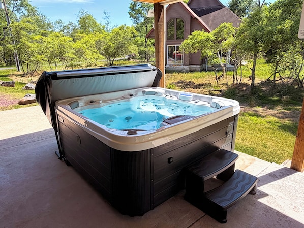 A hot tub with a wooden exterior, a built-in bench, and a step for access.