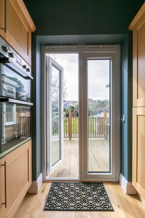 A modern kitchen with a sliding glass door leading to a wooden deck.
