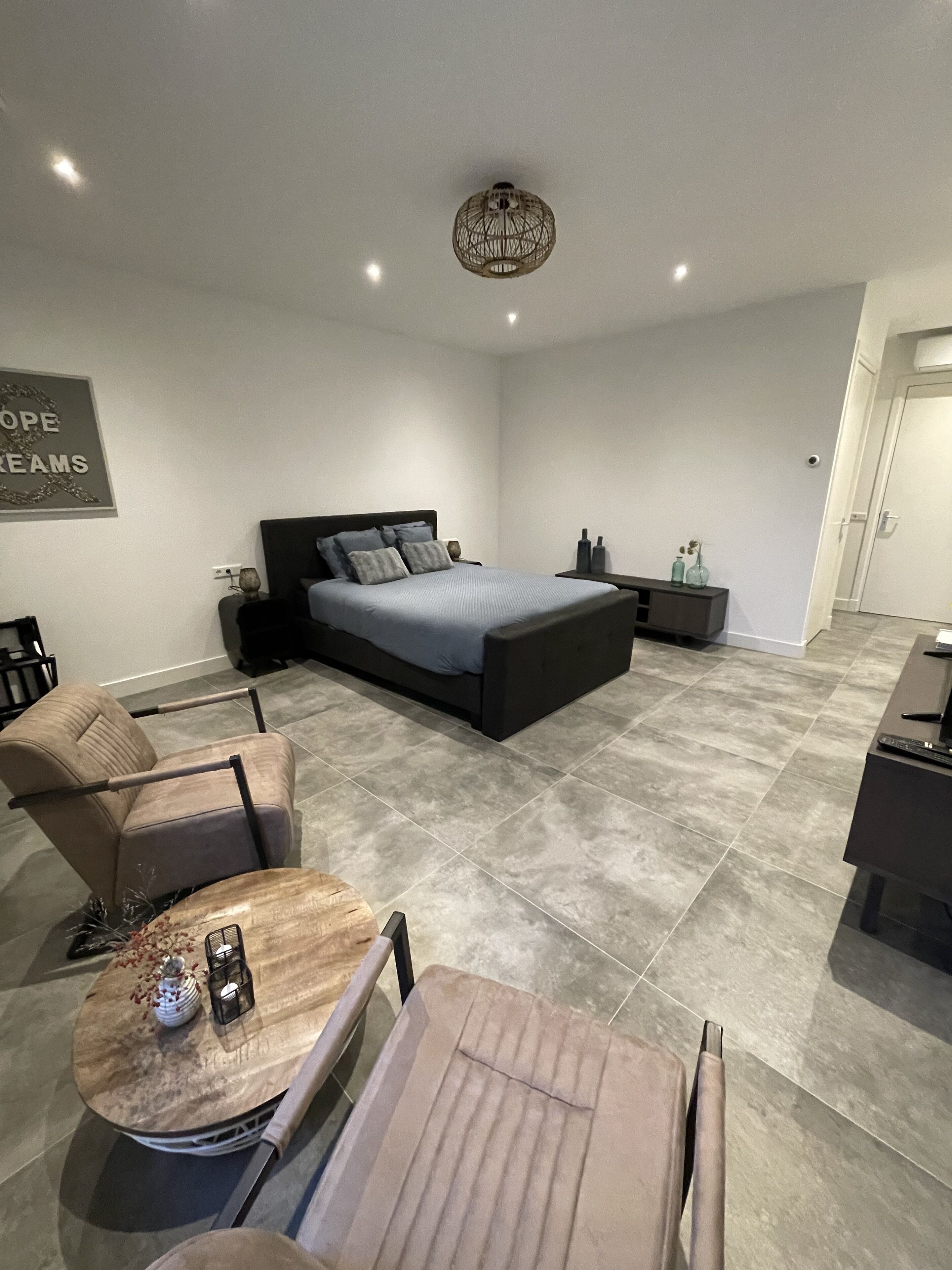 Une chambre moderne avec un grand lit, un coin salon avec une table et une petite table d’appoint agrémentée d’objets décoratifs.