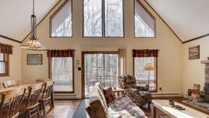 Un salon spacieux avec un haut plafond, des meubles en bois, une cheminée et de grandes fenêtres.