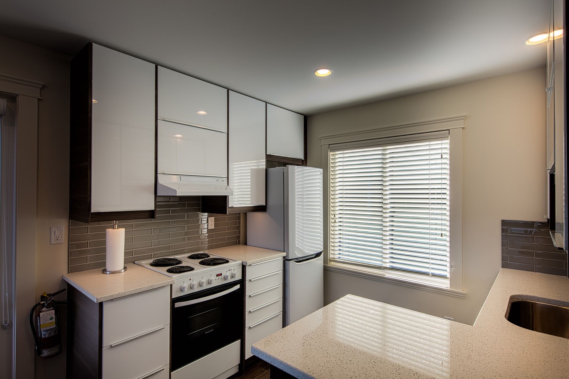 A compact kitchen with white cabinets, a stove, oven, and a refrigerator.