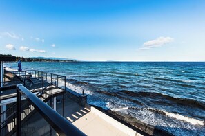 A seaside promenade with a glass balustrade overlooking the ocean. - Qualicum Beach Ocean Suites  (Qualicum Beach)