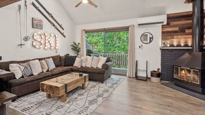 A cozy living room with a brown sectional sofa, a wooden coffee table, and a fireplace. - Prime Location on Camelback Mtn, Renovated w/ Movie & Game Room | The Bear's Den (Tannersville)