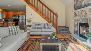A living room with a sofa, coffee table, fireplace, and kitchen in the background.