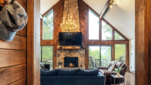 Amplia sala de estar con chimenea de piedra, un televisor grande y un alto techo con vigas de madera.