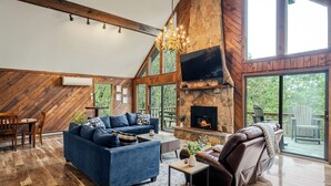 Un salón amplio con un sofá azul grande, un sillón de masaje, una chimenea y un televisor.