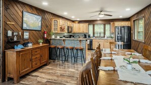 Una cocina con armarios de madera, una zona de bar y una mesa de comedor preparada para cuatro personas.