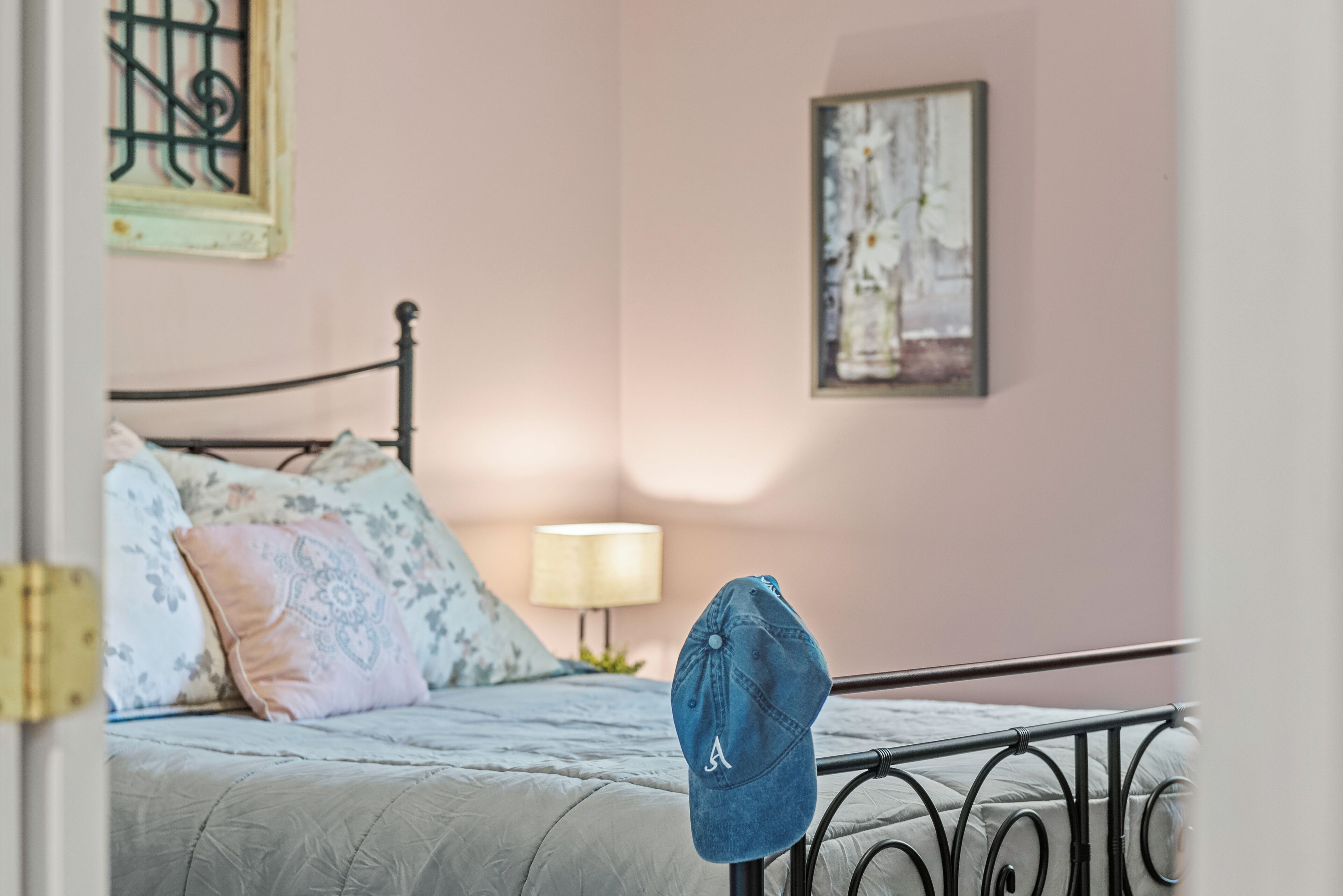 A bedroom with a bed, pillows, a lamp, and a wall with a painting.