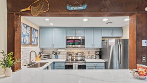 Una cocina moderna con armarios azul claro, electrodomésticos de acero inoxidable y encimera de mármol.