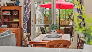 Un comedor con mesa de madera, sillas, una planta en maceta y un paraguas rojo.