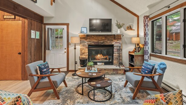 Una sala de estar acogedora con chimenea, dos sillones, un sofá y una mesa de centro.