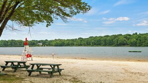 A beach with picnic tables and a lifeguard stand. - Ridge Retreat by AvantStay | Game Room, Covered Porch, & Fire Pit! (Blakeslee)