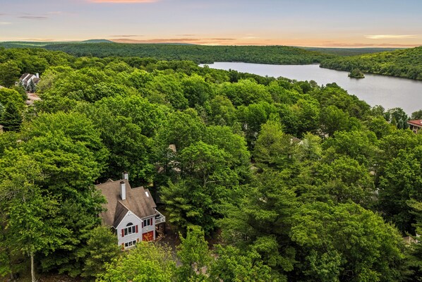 A house surrounded by dense forest with a lake in the background. - Lake Harmony Retreat • Fire Pit + Game Room • Near Big Boulder | The Boulder Inn (Lake Harmony)