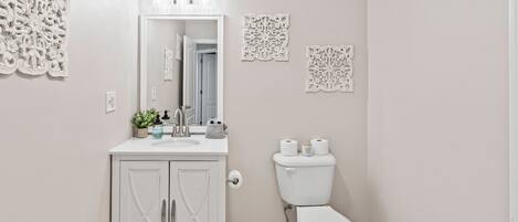 Un baño con tocador blanco, inodoro y decoración mural.