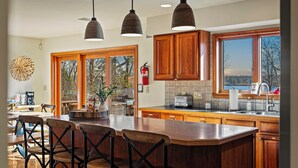 Una cocina amplia con armarios de madera, una isla grande con taburetes de bar y vistas al exterior a través de ventanas grandes.