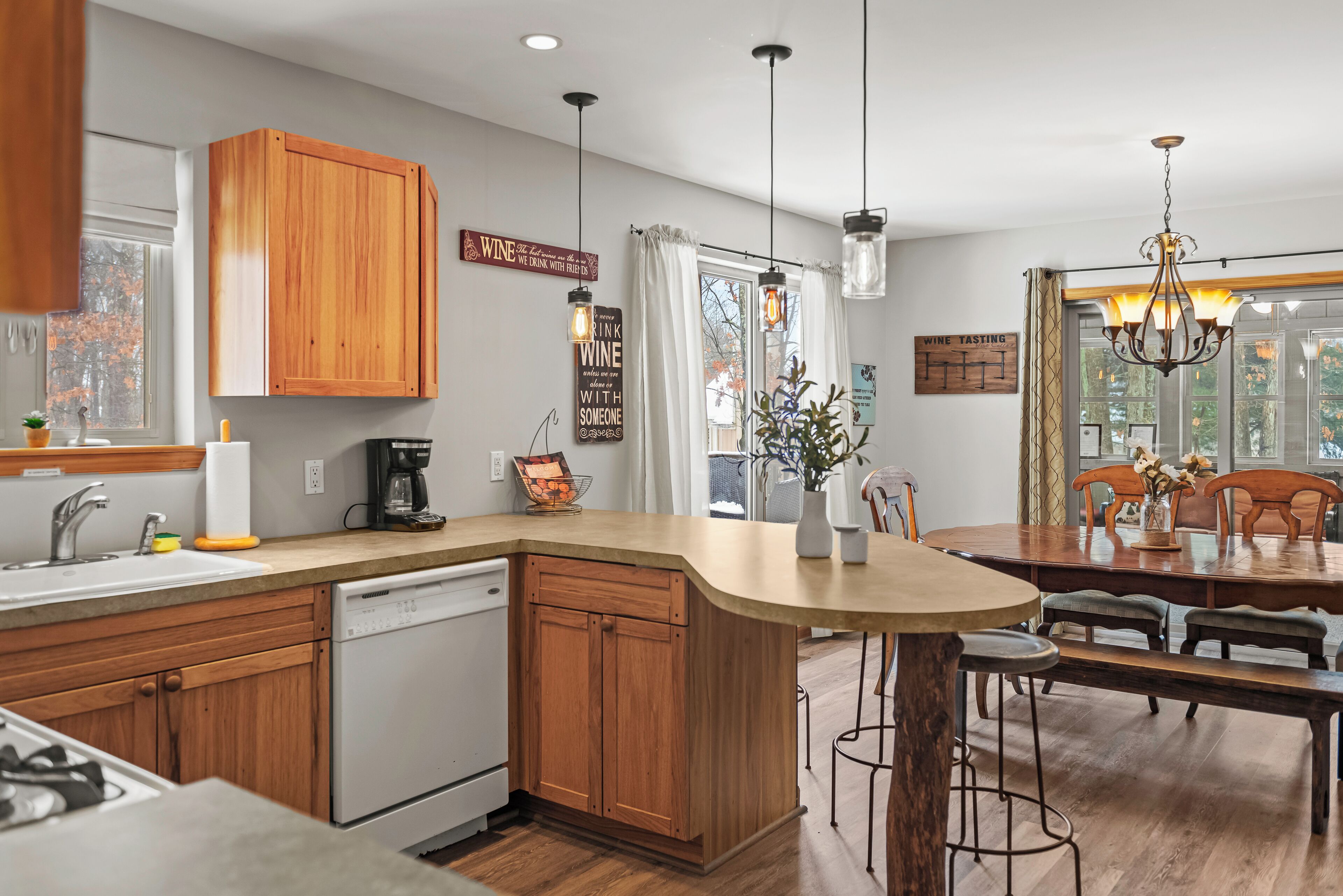 A modern kitchen with wooden cabinets, a dishwasher, and a dining area with a wooden table and chairs.
