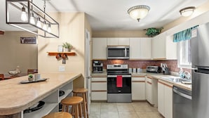 A modern kitchen with a central island, stainless steel appliances, and wooden stools.