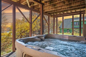 Ein Whirlpool mit Holzkonstruktion und Blick auf ein grünes Haus im Hintergrund.