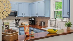 A kitchen with blue cabinets, a microwave, a toaster, and a sink.