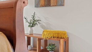 A wooden console table with a yellow macrame throw, a white vase with a plant, and a small potted plant.