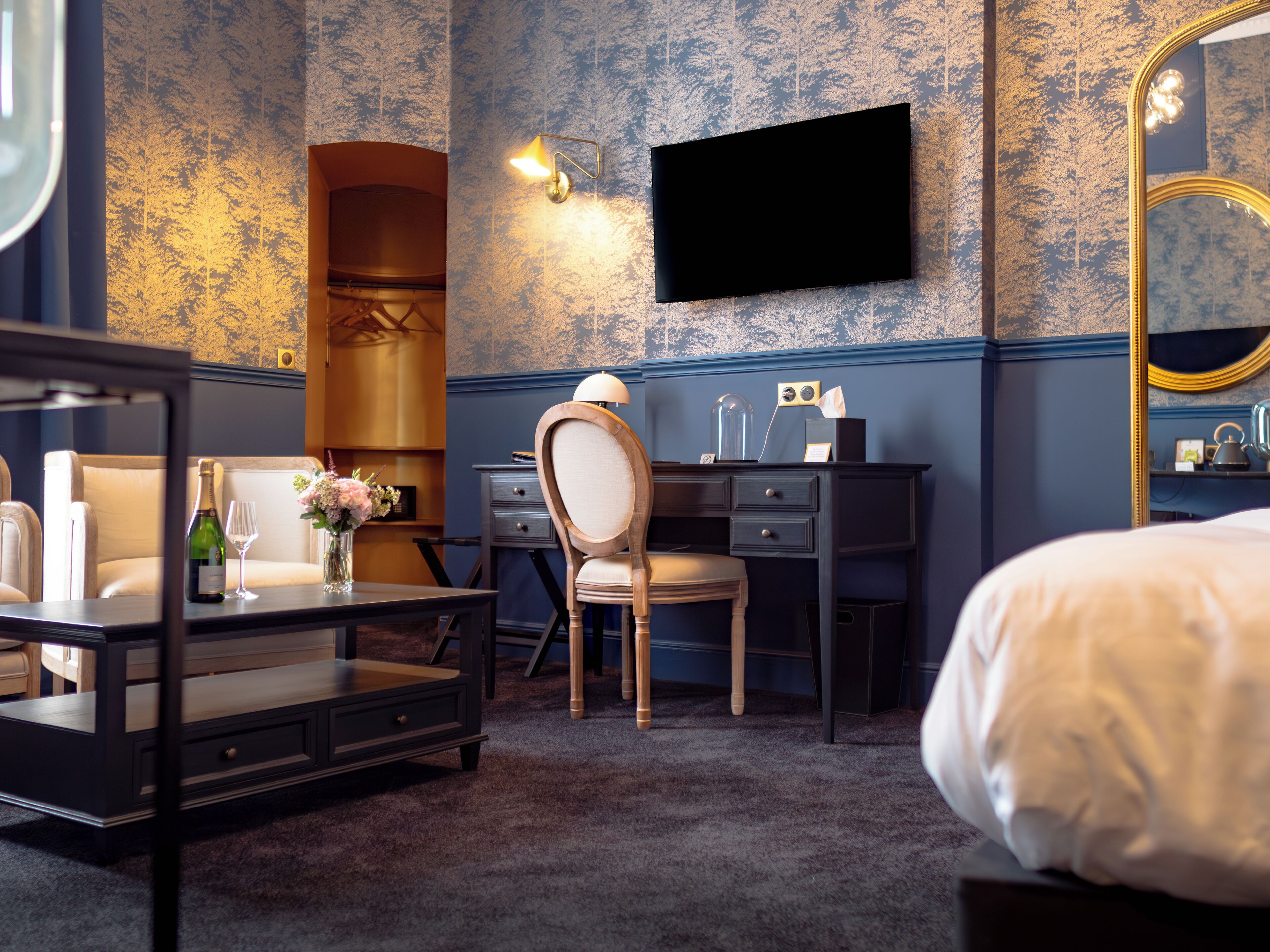 Una habitación de hotel con cama, escritorio, silla, cómoda, espejo y televisor.
