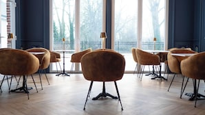 A dining area with wooden flooring, large windows, and several round tables with chairs. - Hotel Château Héloïse (Mérélessart)