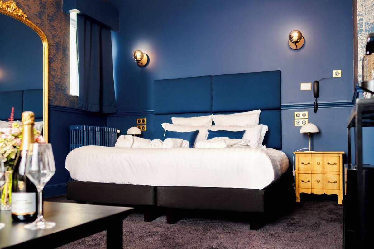 Un dormitorio con una cama grande, una mesita de noche con lámpara, un aparador y un espejo.