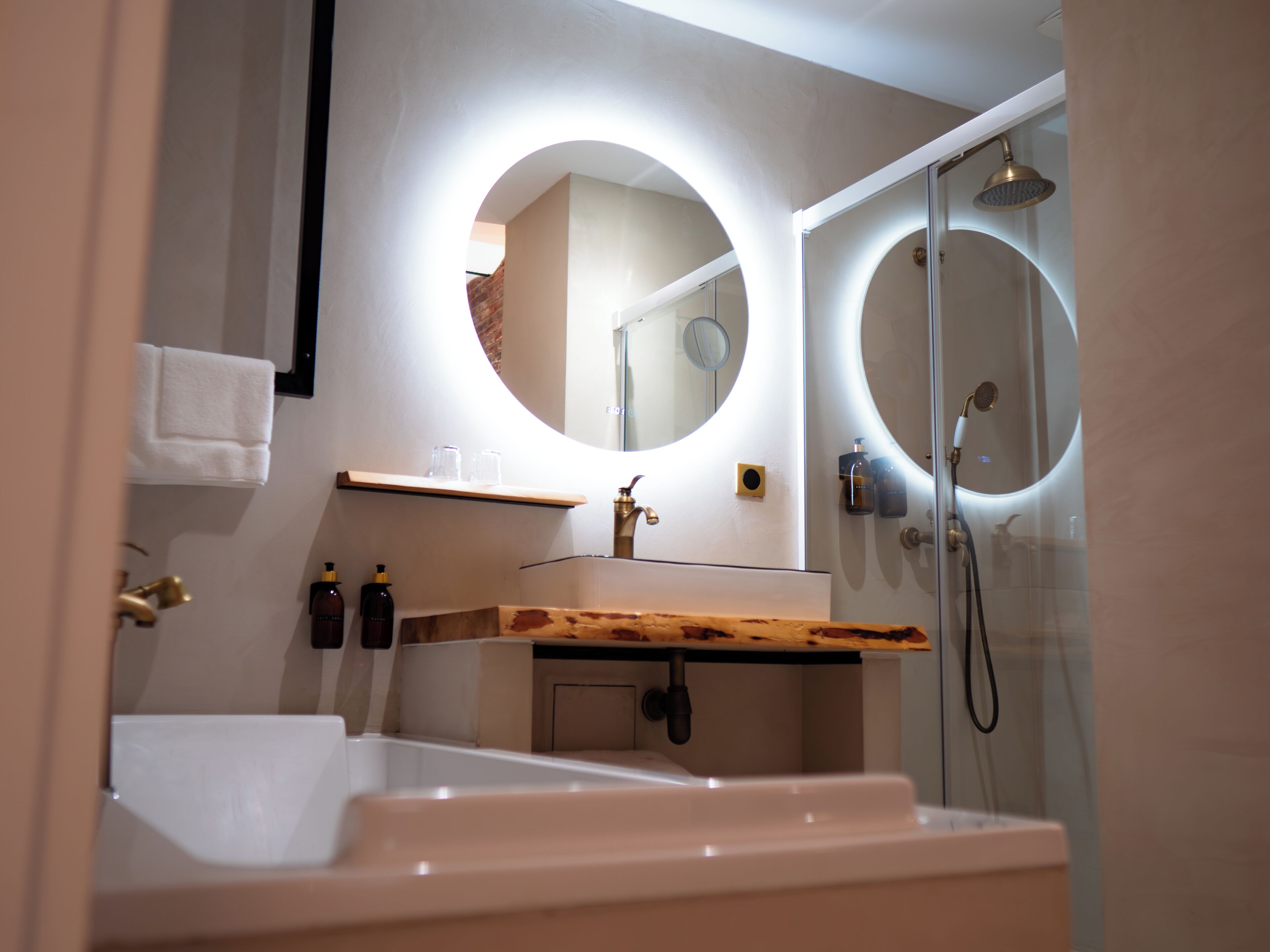 A modern bathroom with a bathtub, a sink with a wooden countertop, and a shower with a glass door.
