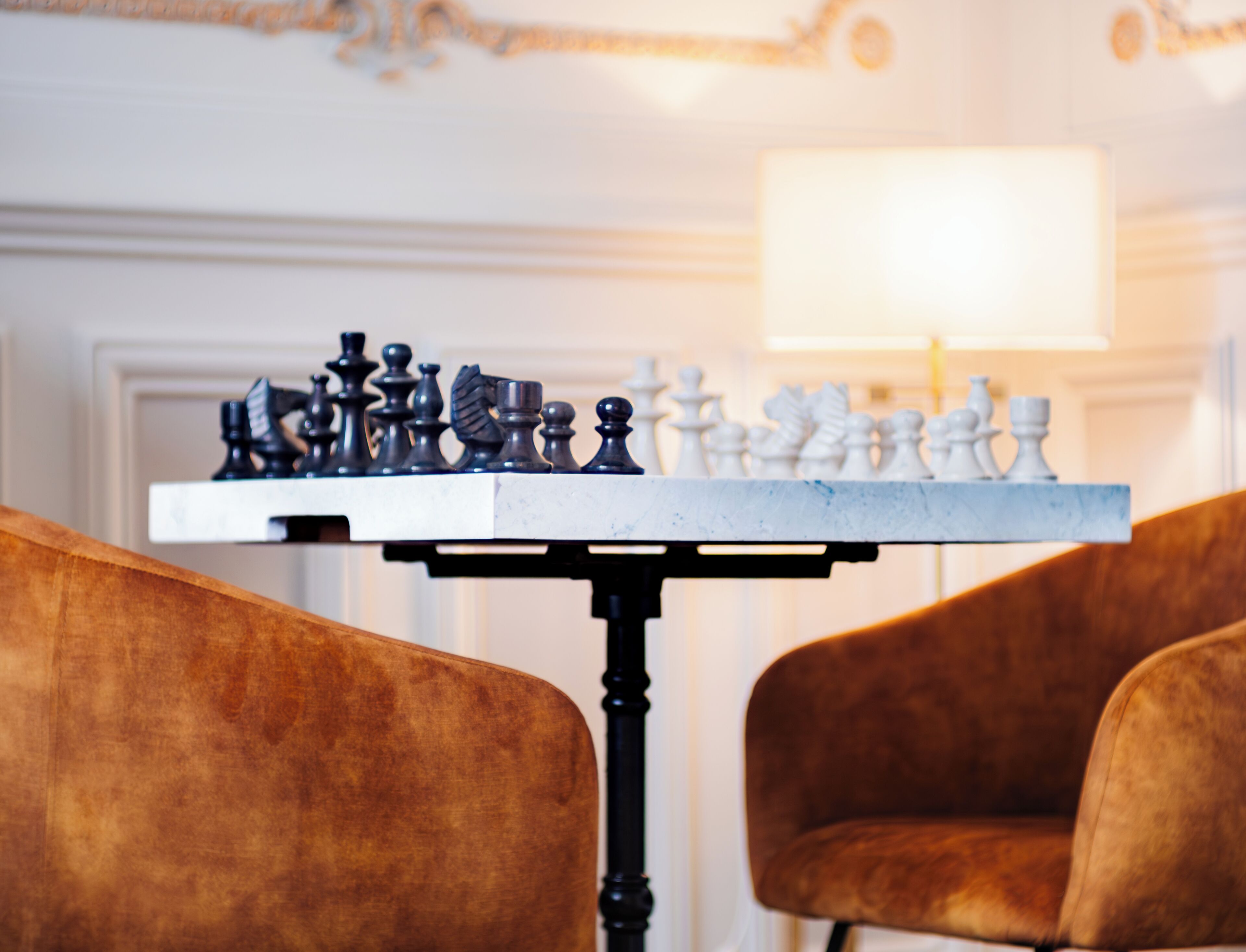 A chessboard on a table with two chairs.