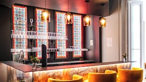 A bar area with a marble countertop, multiple glasses, and a stained glass window. - Hotel Château Héloïse (Mérélessart)