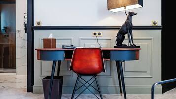 Een bureau met een lamp, een stoel en een beeldje.