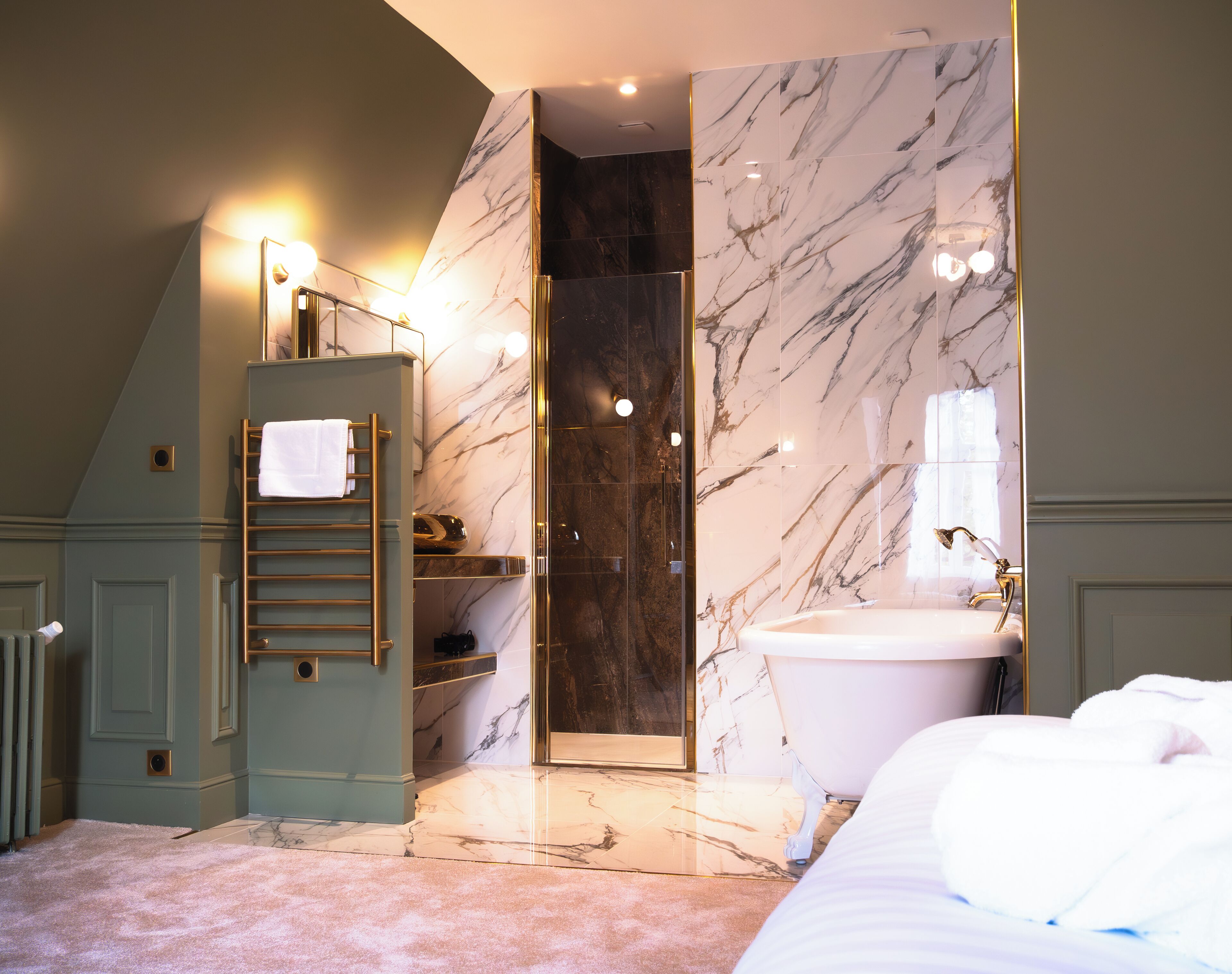 A modern bathroom with a marble shower, a freestanding bathtub, and a towel rack.