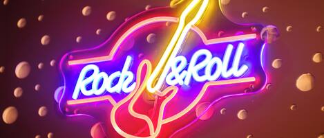 Un letrero de neón con el texto "Rock & Roll" sobre un fondo oscuro y objetos esféricos flotantes.