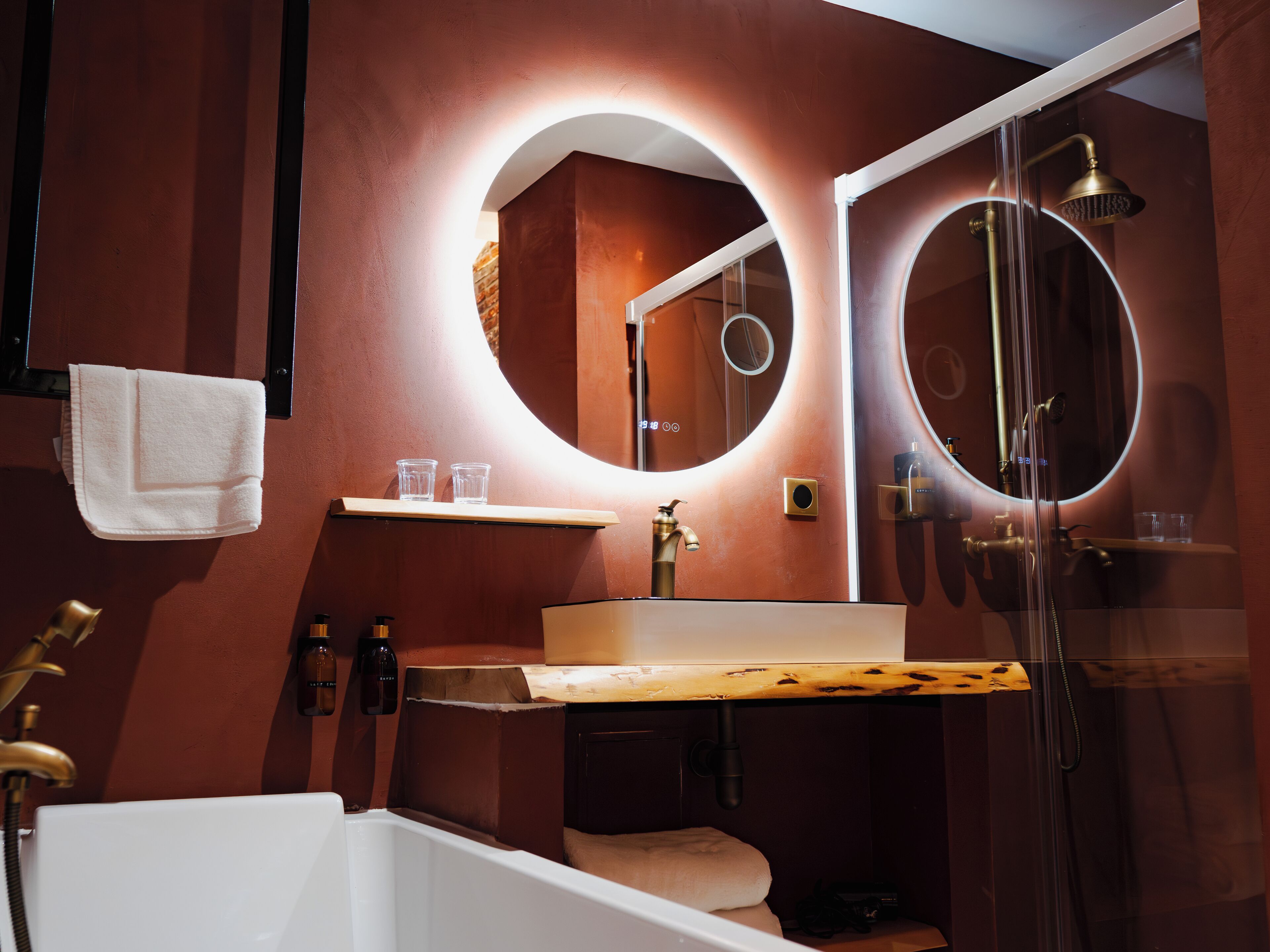 A modern bathroom with a white bathtub, a vanity with a mirror, and a glass-enclosed shower.