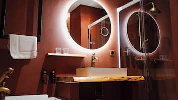 A modern bathroom with a white bathtub, a vanity with a mirror, and a glass-enclosed shower.