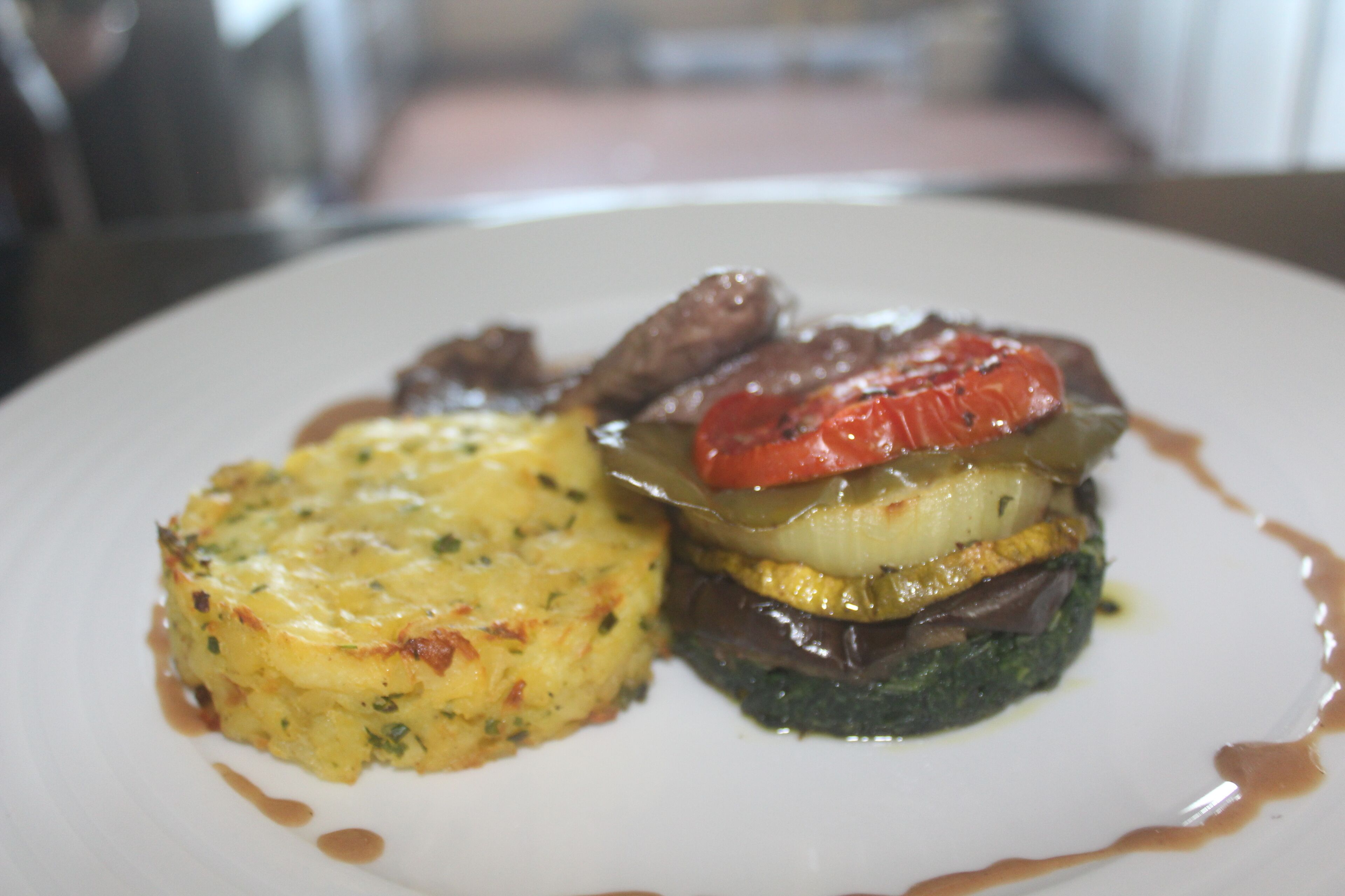 Un plato con una porción de quiche, un pimiento relleno y un trozo de carne.