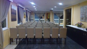 Una sala de conferències amb files de cadires, una taula llarga i vista a un balcó.