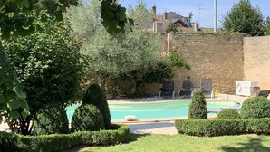 A swimming pool surrounded by well-maintained hedges and a stone wall.